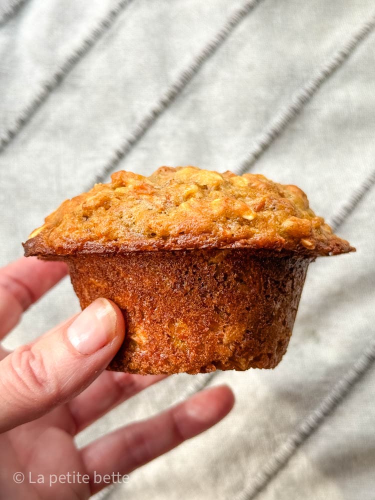 muffin aux carottes dans la main d'une femme devant un linge ligné