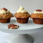 trois muffins aux carottes et à l'avoine avec glaçage au fromage à la crème, noix de pacane sur un support à gâteau
