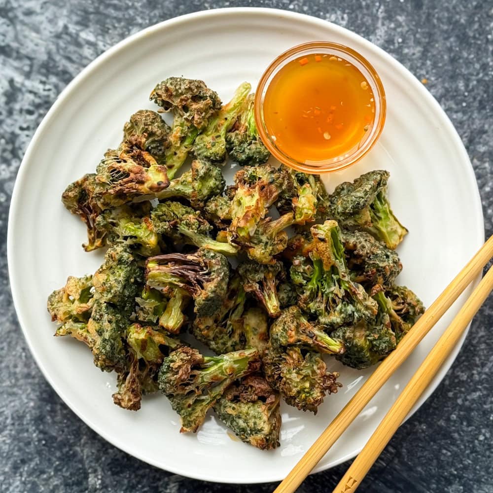 bouchées de brocoli croustillant dans une assiette blanche avec sauce nuon mam et chopsticks