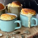 3 soufflés au fromage dans des tasses à café sur une planche en bois
