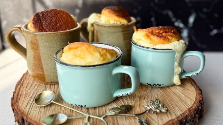 4 soufflés au fromage individuels dans des tasses à café sur une planche de bois avec cuillères