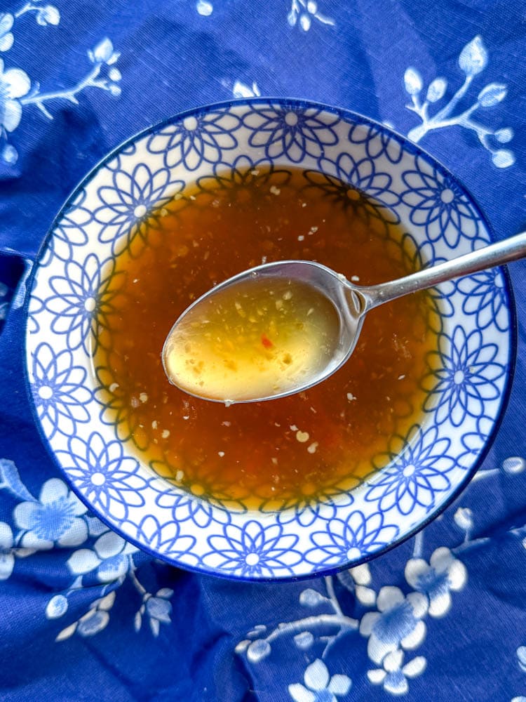sauce nuoc mam dans un bol fleuri bleu et blanc avec cuillère  sur un linge bleu fleuri