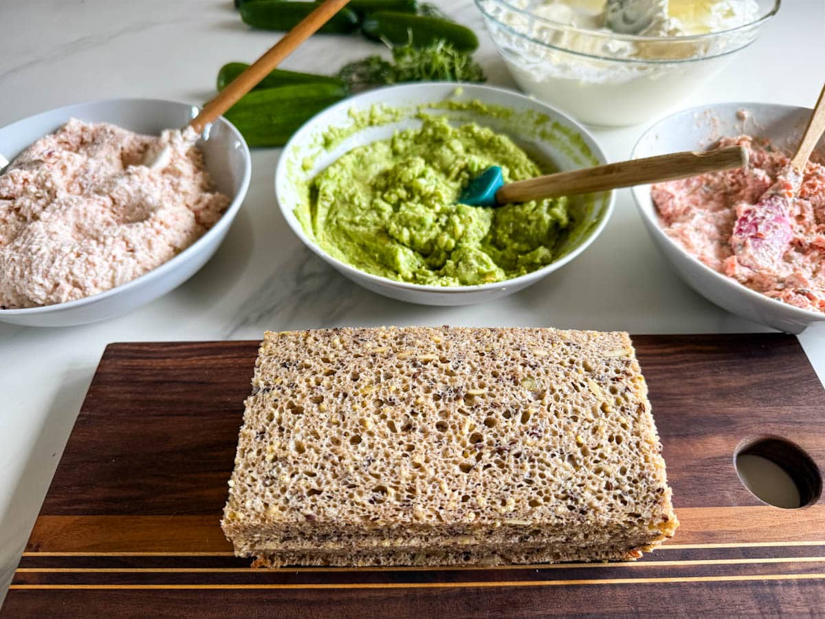 trois bols de garnitures à pain sandwich et tranches de pain en avant sur une planche