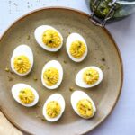 oeufs mimosa aux herbes salées mayonnaise dans une assiette poterie avec pot d'herbes salées