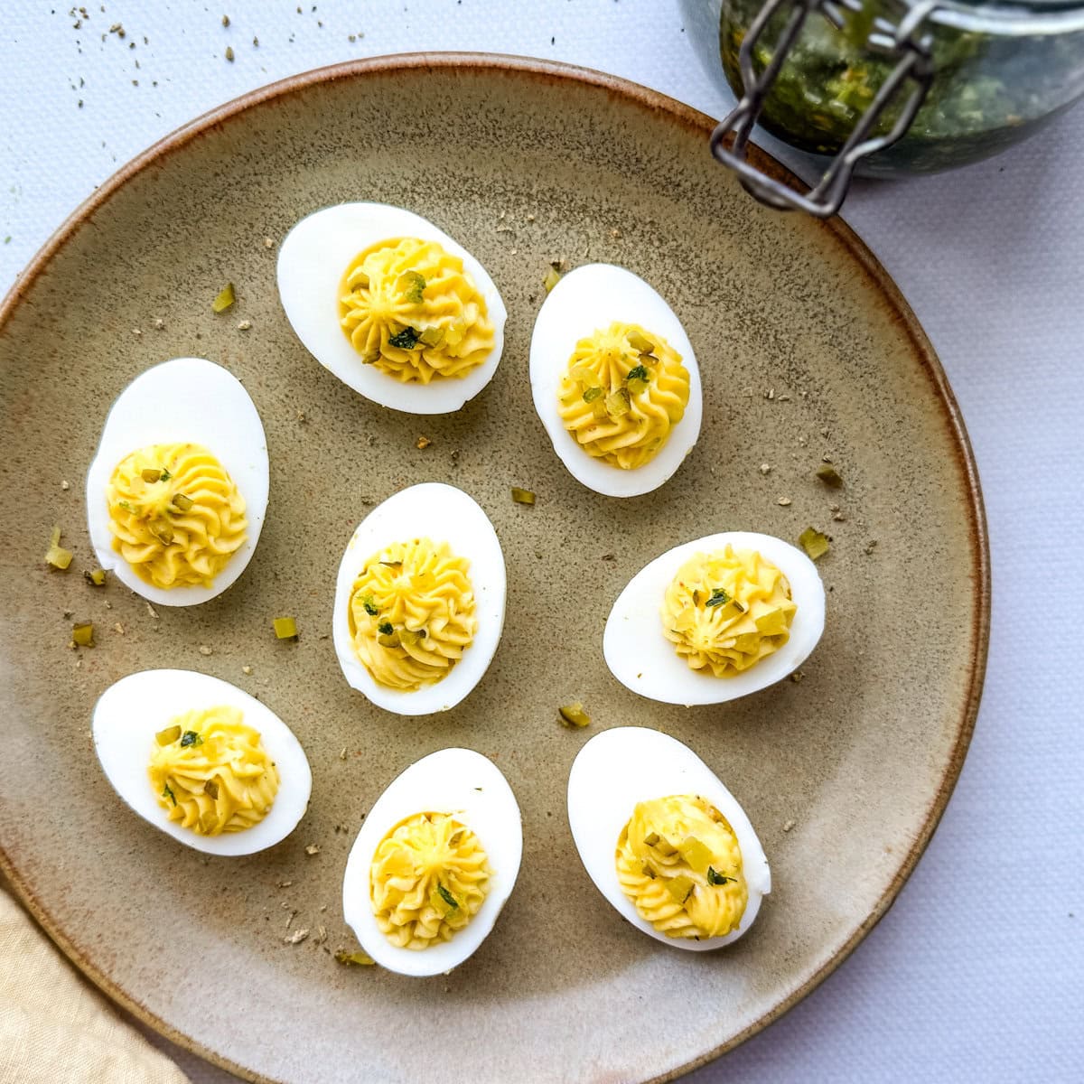 oeufs mimosa aux herbes salées mayonnaise dans une assiette poterie avec pot d'herbes salées