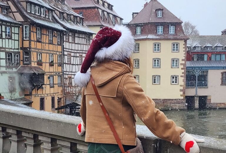 Manon Lapierre de dos avec chapeau de Noël devant maisons alsaciennes sous la neige