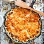 gratin dauphinois gratiné dans une grade poêle en fonte sur une table festive avec cuillère de bois