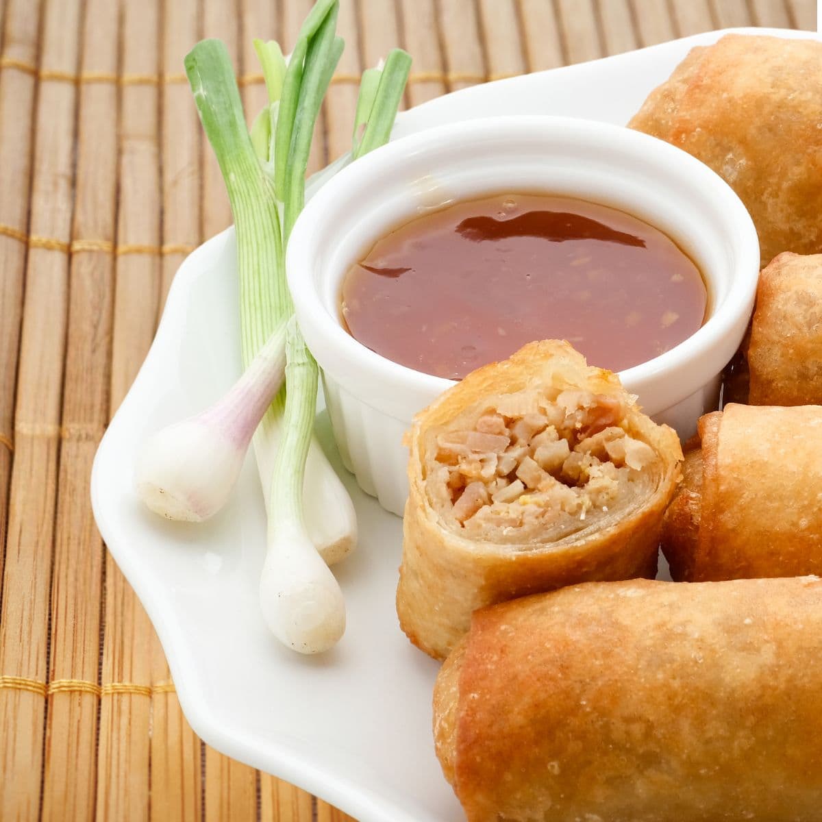 rouleaux impériaux avec sauce nuoc mam dans une assiette sur tapis de bambou