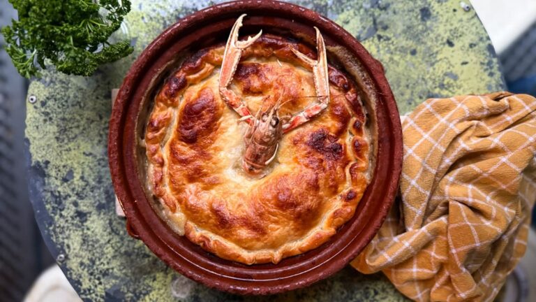 casserole de fruits de mer avec pâte feuilletée style marmite dieppoise sur une table en marbre avec linge de table jaune