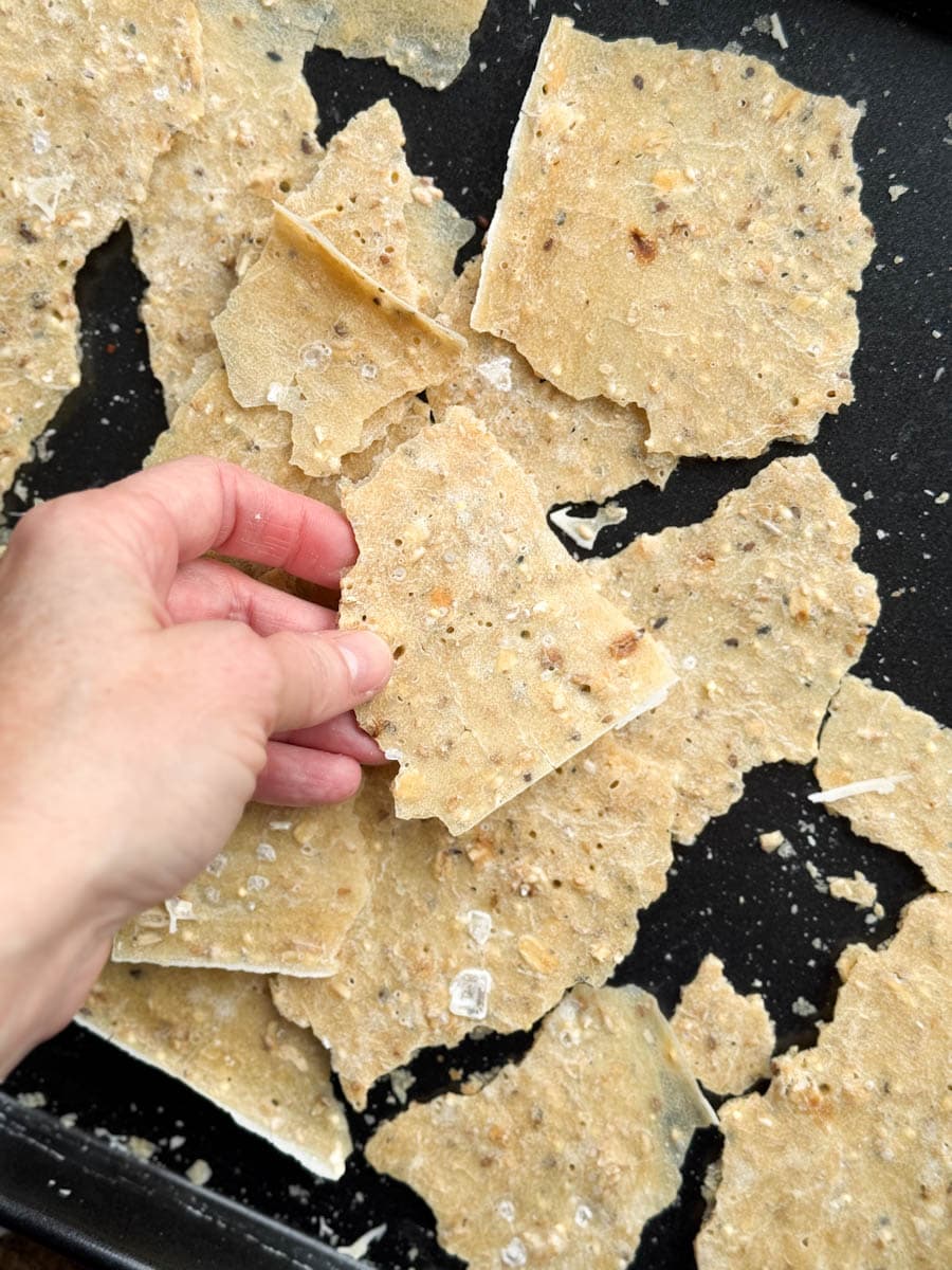 main tenant des craquelins au levain garnis de flocons de sel et graines de sésame