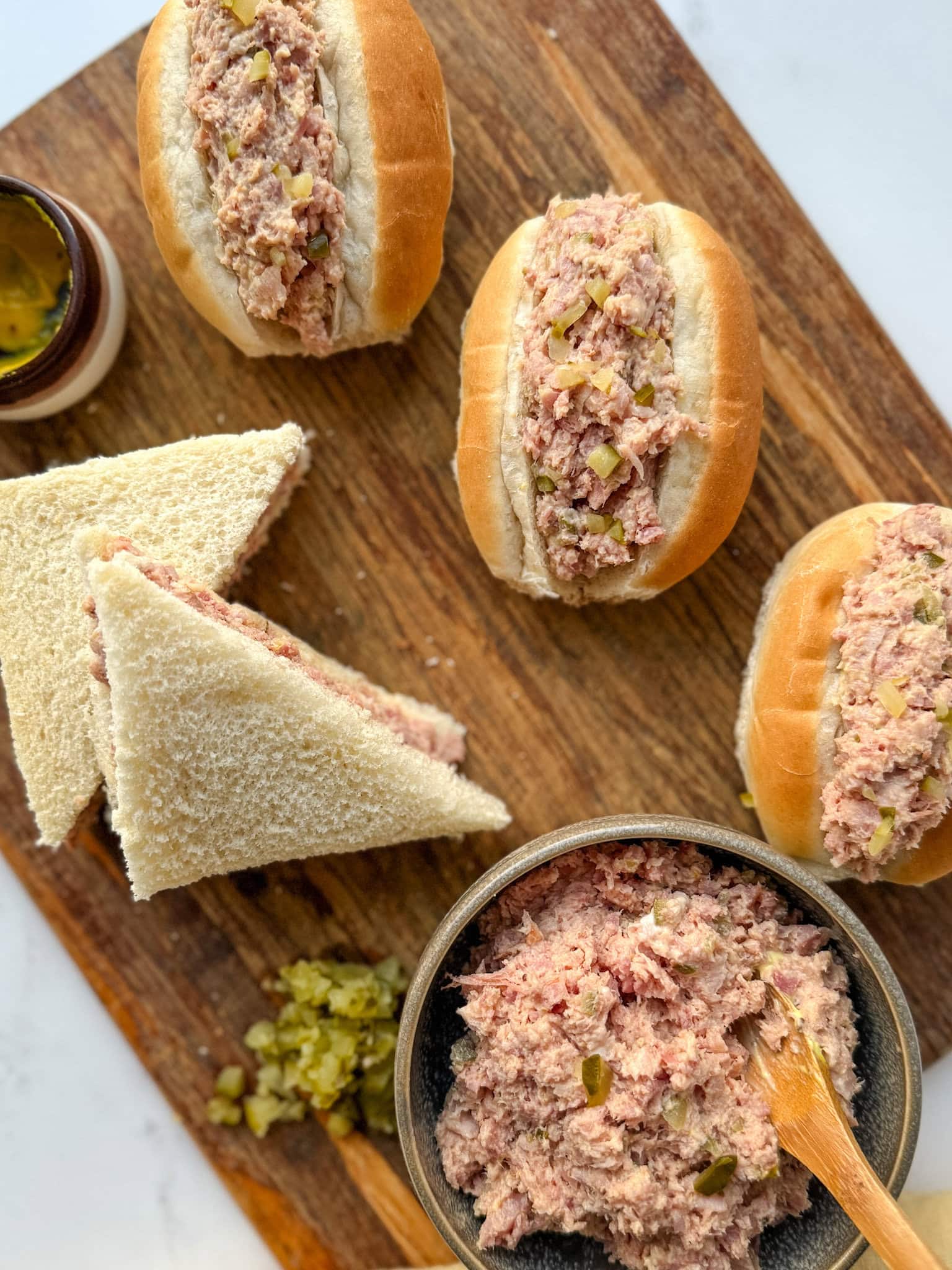 sandwich au jambon haché, petit pain fourré à la salade de jambon, cornichons haché sur une planche en bois