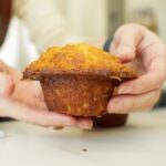 mains tenant un muffin au caramel avec un chapeau