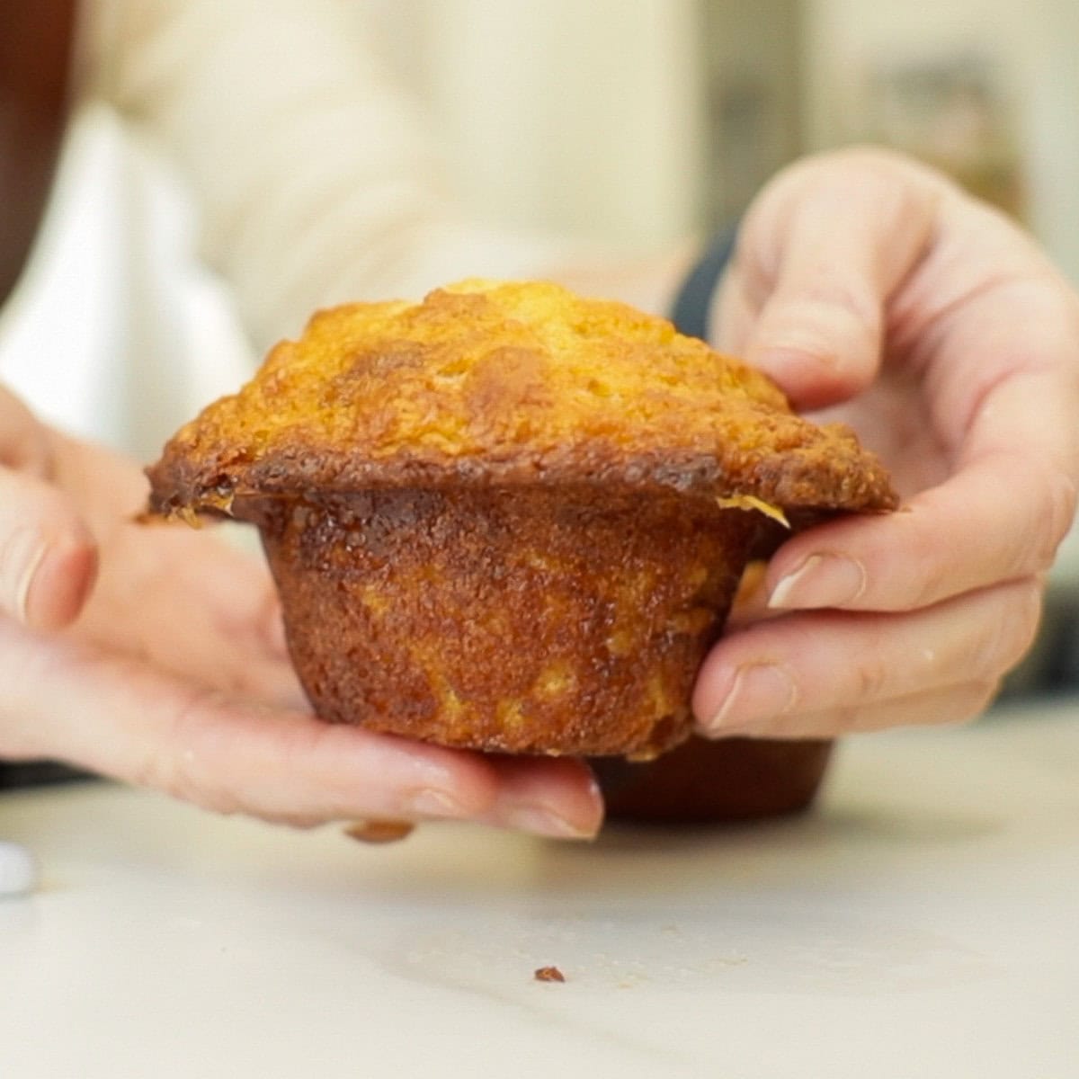 mains tenant un muffin au caramel avec un chapeau