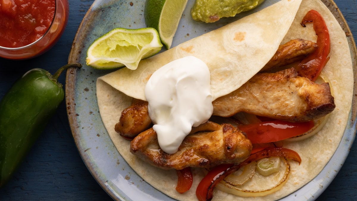poulet grillé style mexicain fajitas dans une tortilla avec crème sure, citron vert et légumes grillés