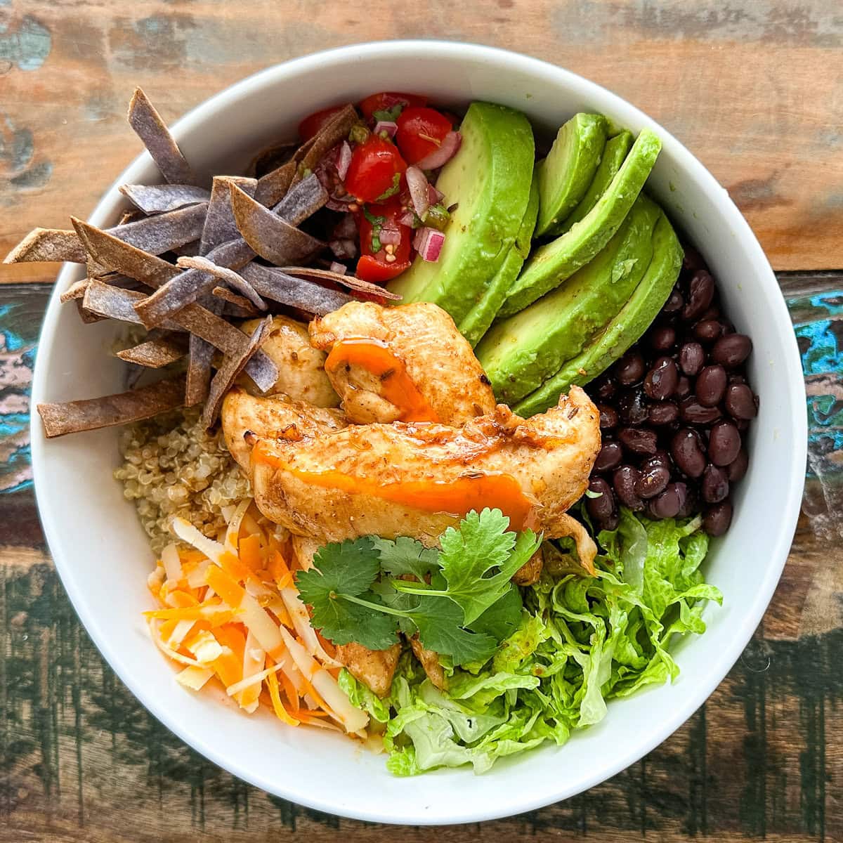 bol repas style poulet rouge avec tortilla, poulet grillé et sauce, avocat, haricots noirs et fromage