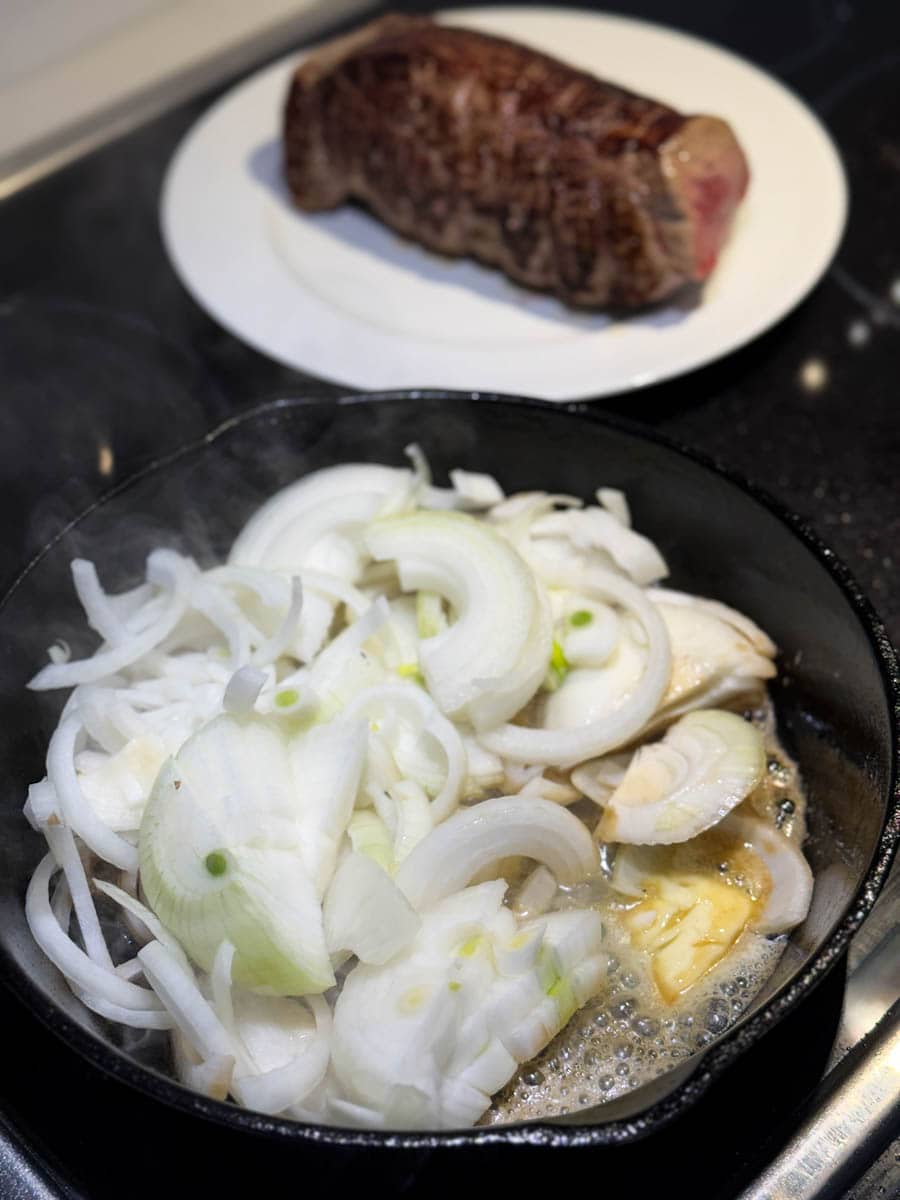 oignons et beurre dans la poele en fonte avec rôti français en arrière plan