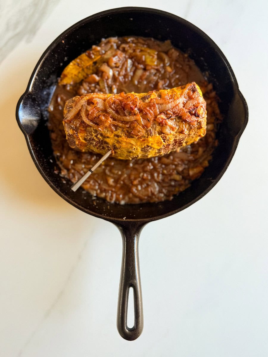 rôti français grillé sur un lit d'oignons dans une poêle en fonte