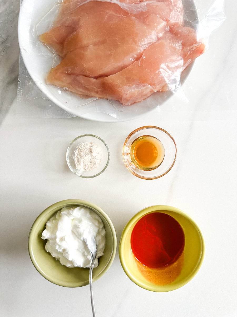 poitrines de poulet, deux petits bols (sirop d'érable, sel d'ail) et deux moyens bols (yogourt et sauce Buffalo)