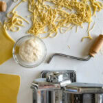 pâtes fraîches maison, machine à pâte, bol avec levain sur comptoir blanc