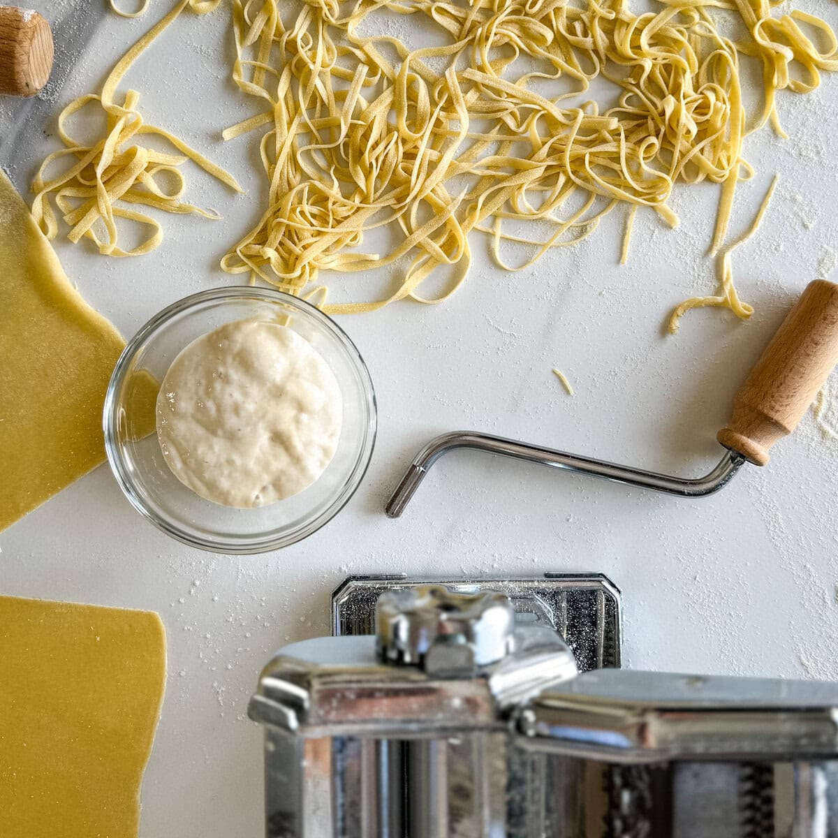pâtes fraîches maison, machine à pâte, bol avec levain sur comptoir blanc