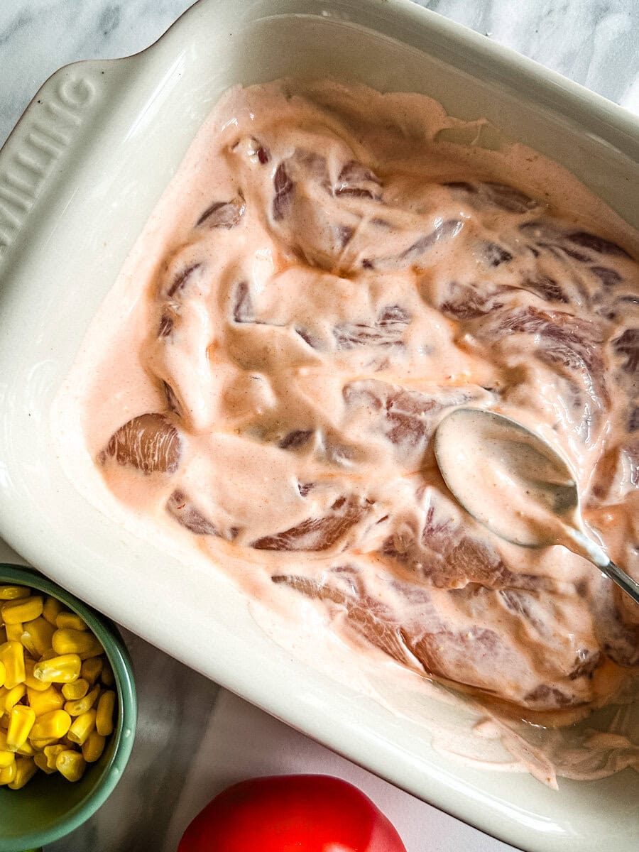 poitrines de poulet dans une marinade rosée crémeuse dans un plat rectangulaire