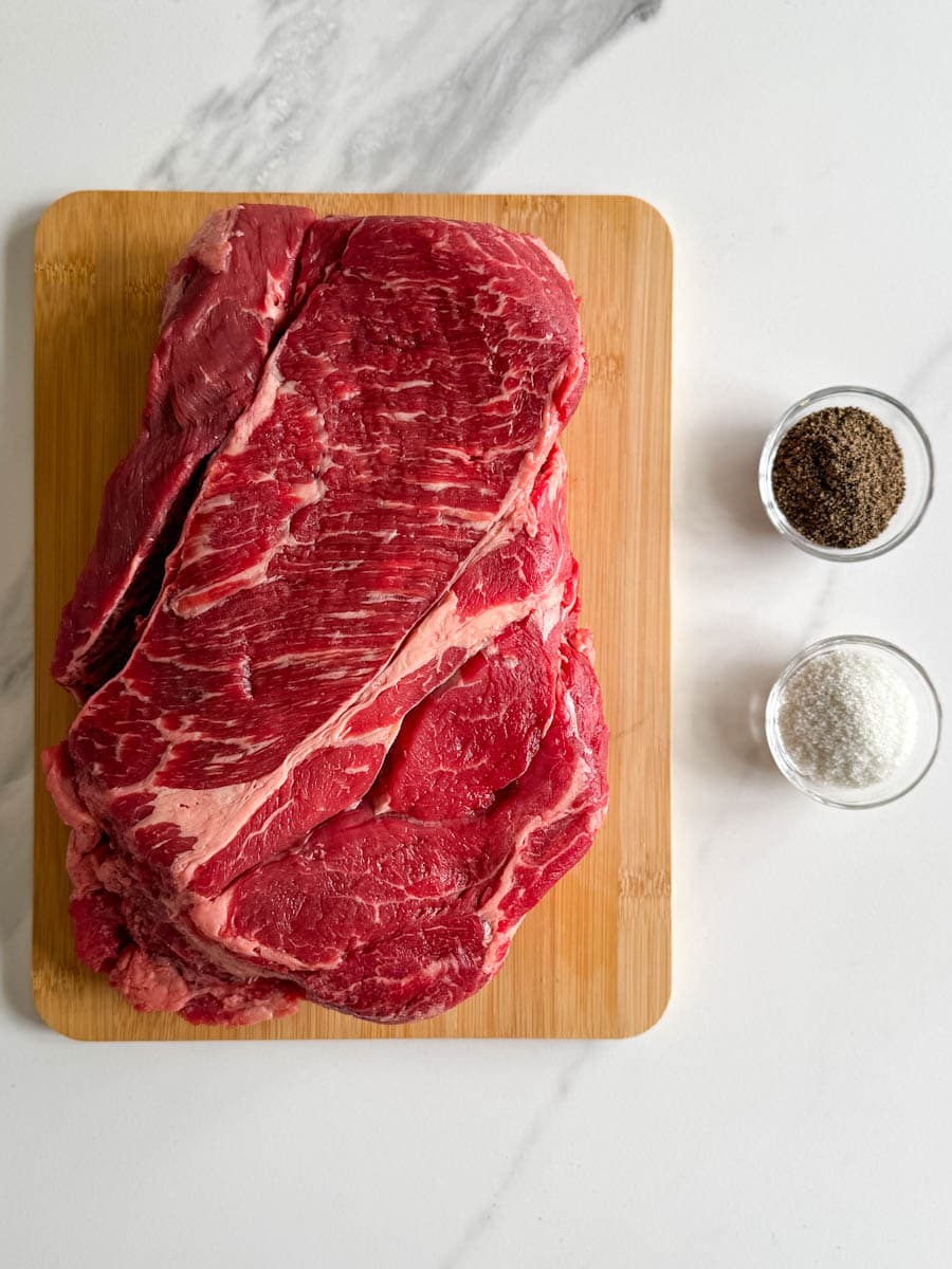 rôti de palette de boeuf sur une planche, petit bol de sel et poivre