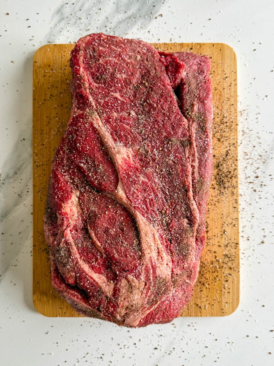rôti de palette de boeuf assaisonné de sel et poivre sur une planche