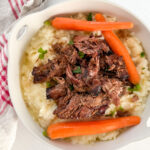 palette de boeuf effiloché avec carottes sur purée de pomme de terre dans un plat rond blanc