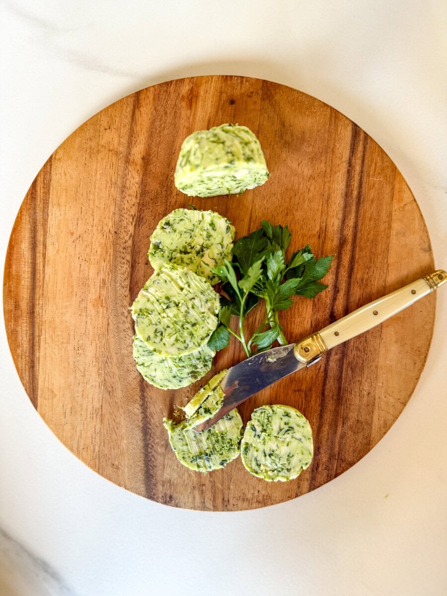 beurre à l'ail en rondelles sur planche de bois avec petit couteau et persil frais
