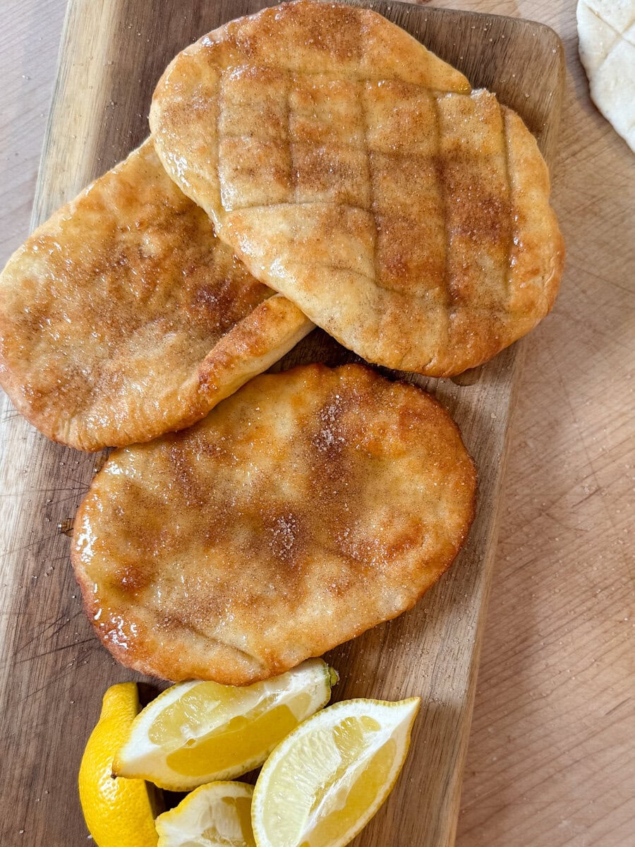 trois queues de castor grillées avec sucre canelle et citron sur une planche en bois