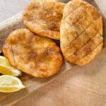 trois queues de castor (beignets) grillés et sucrés avec quartiers de citron sur planche de bois