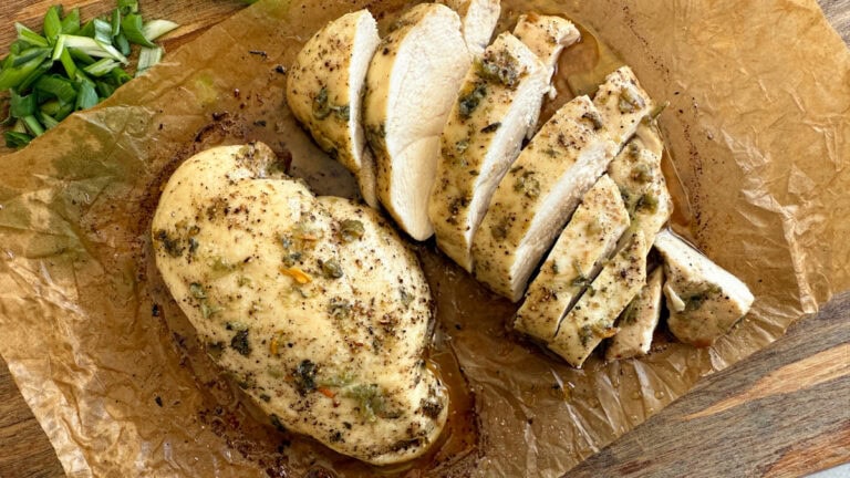 deux poitrines de poulet aux herbes, avec tranches bien juteuses sur une feuille de papier cuisson