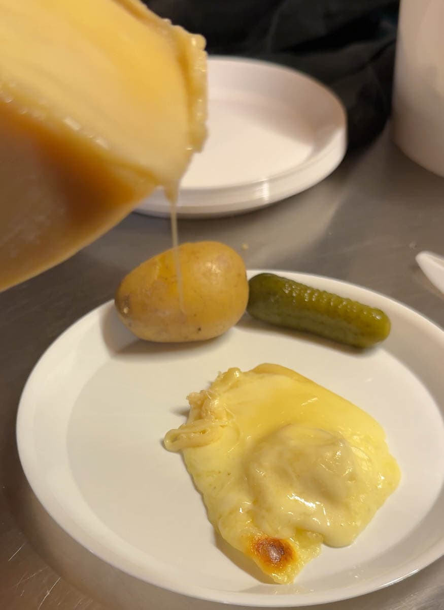 raclette qui font dans une assiette avec une pomme de terre et un cornichon