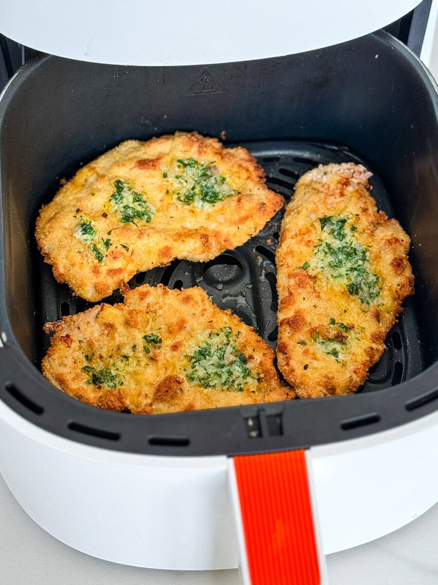 3 escalopes de poitrine de poulet panées au beurre à l'ail dans le panier du air fryer