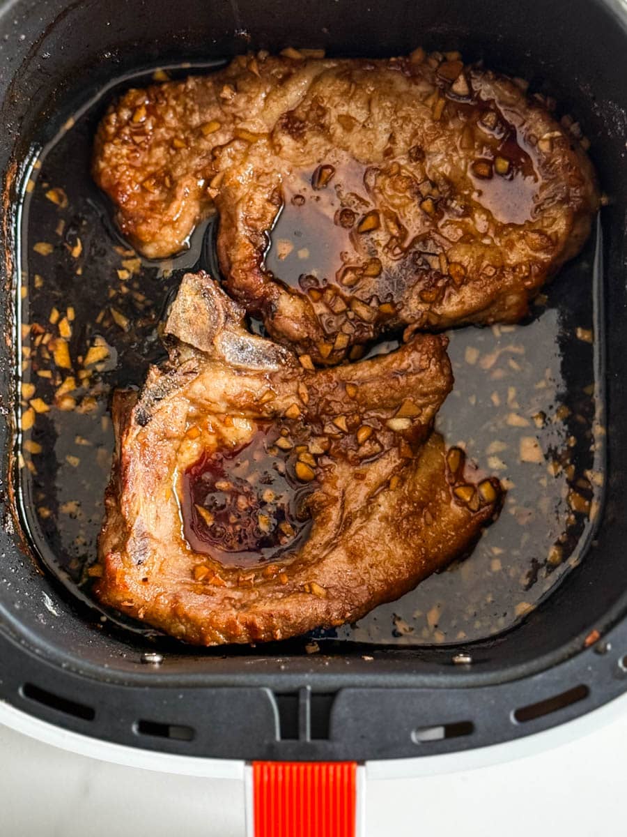 deux cotelettes de porc en sauce dans le bac du air fryer