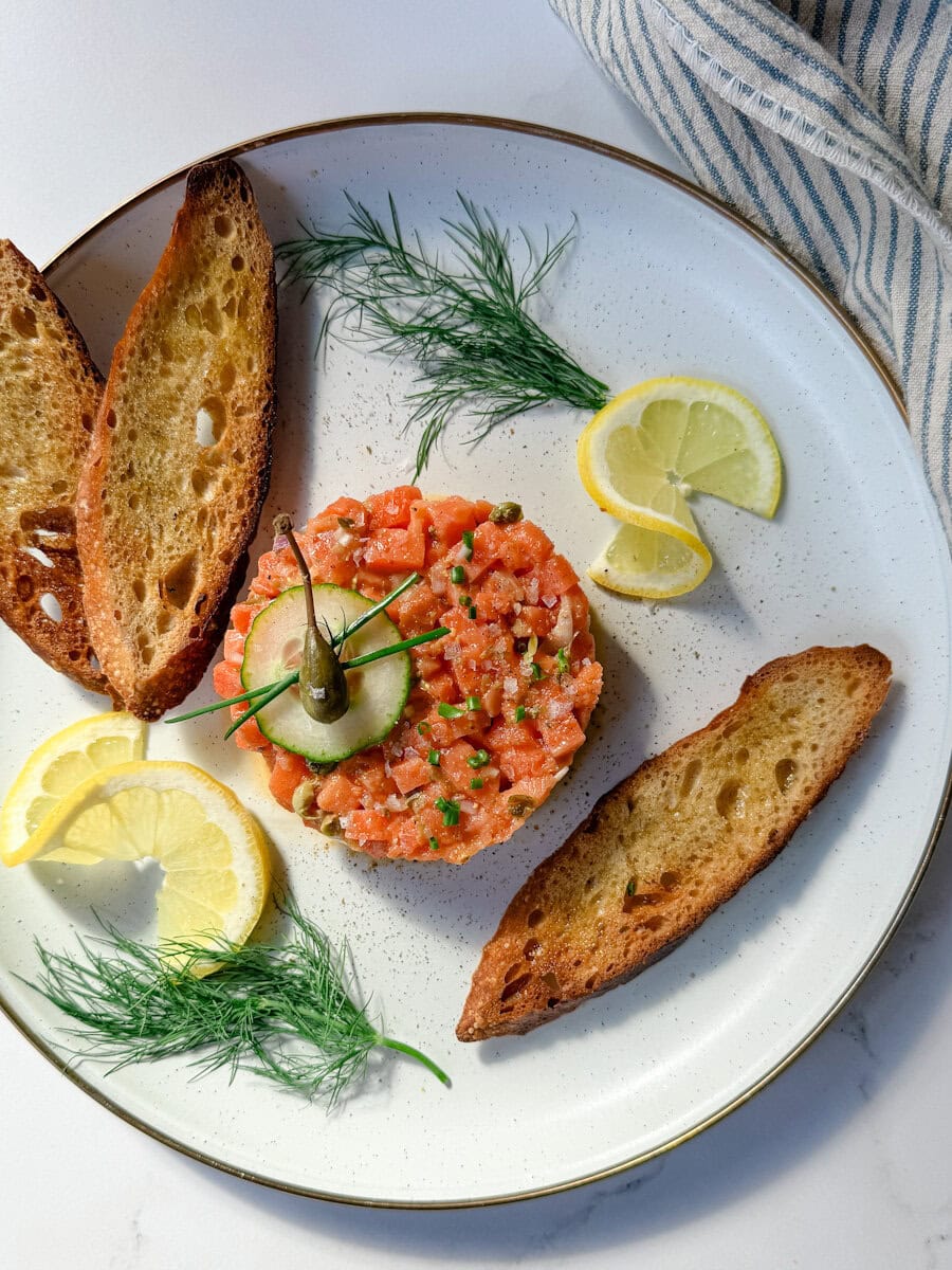 tartare de saumon classique avec citron, croûtons et aneth dans une assiette