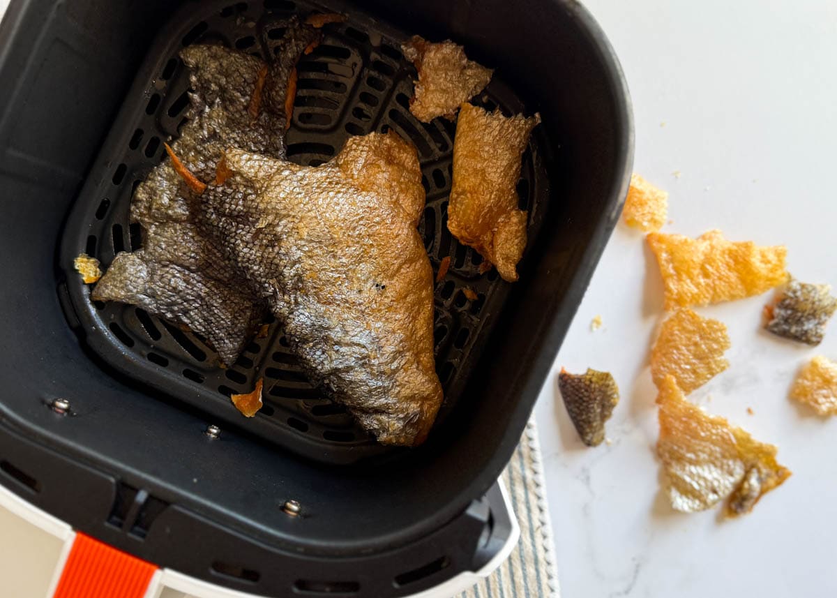 peau de saumon croustillante dans panier de air fryer avec chips de peau de saumon à côté sur comptoir