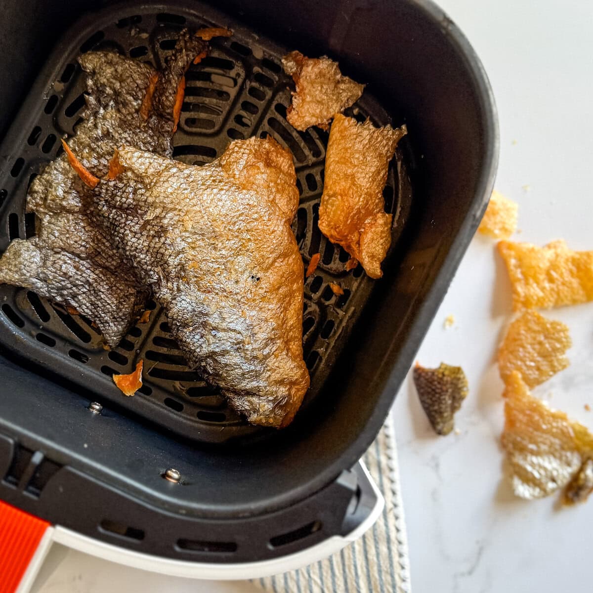 peau de saumon croustillante dans le panier du air fryer avec chips de peau de saumon sur le comptoir