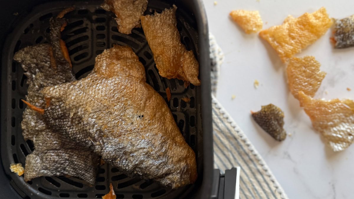 peau de saumon croustillante dans le panier du air fryer avec chips de peau de saumon à côté sur comptoir