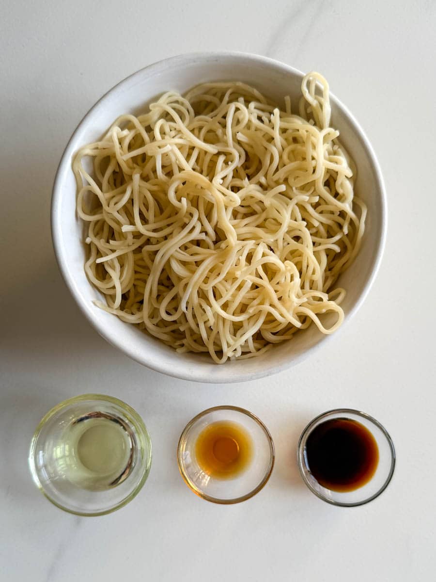 bol de nouilles chow mein, bol d'huile sésame et huile neutre, bol de sauce soja sur comptoir blanc