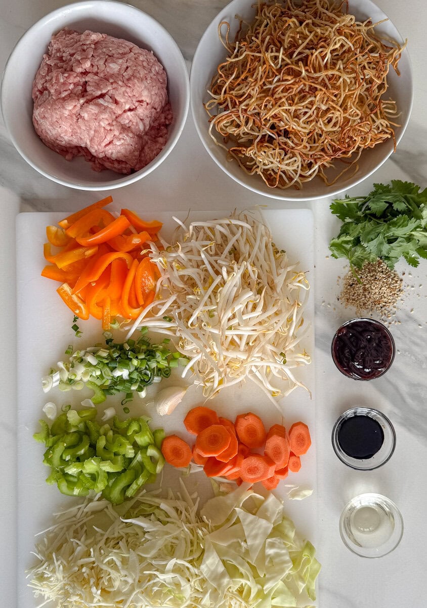 ingrédients chow mein sur comptoir: porc haché, nouilles frites, légumes hachés, sauces