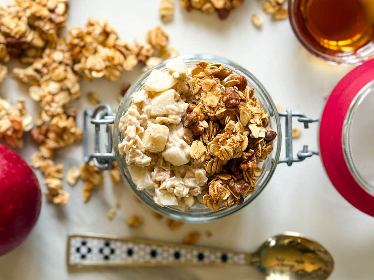 gruau overnight avec garniture granola dans un pot refermable, granola alentour sur comptoir blanc