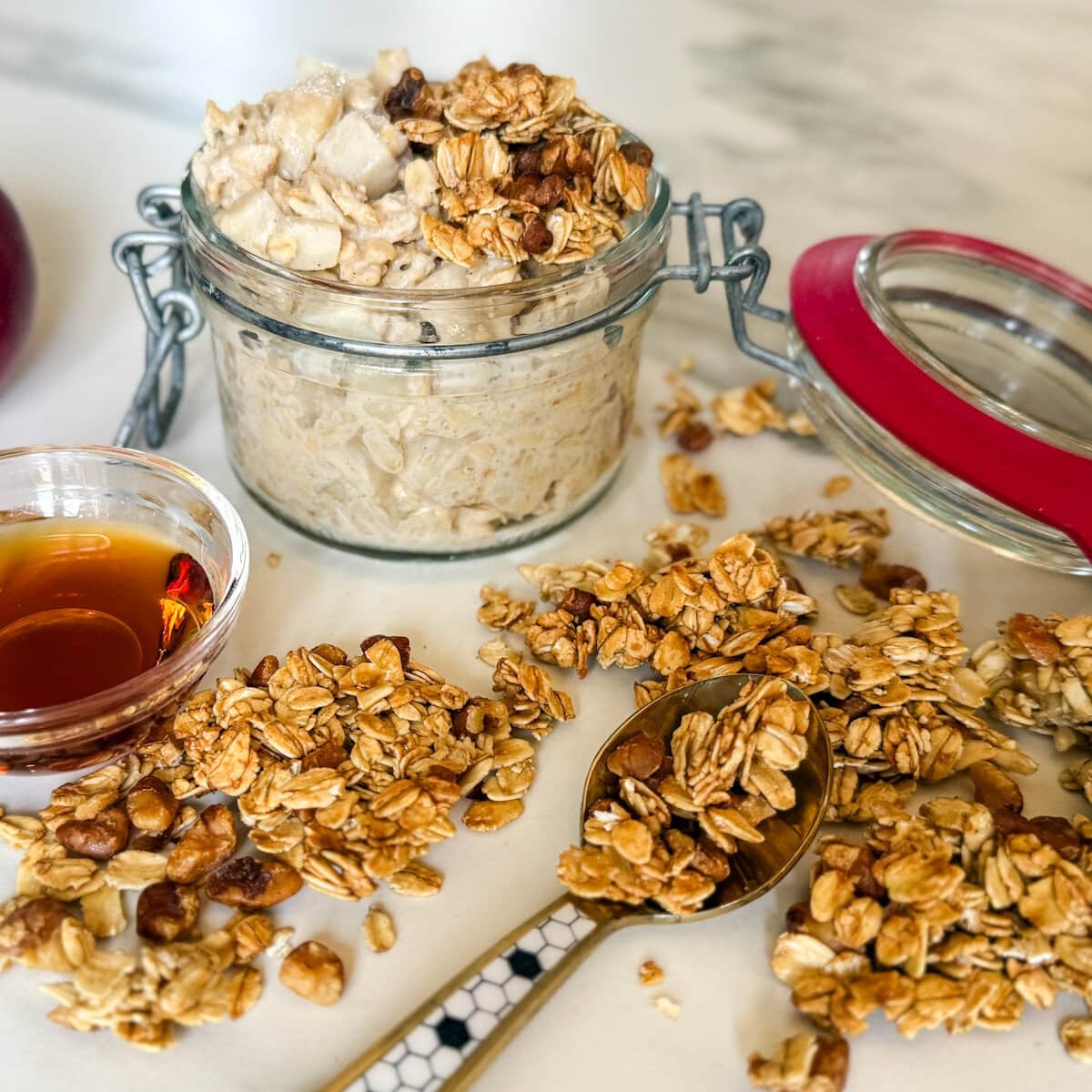 granola grillé sur comptoir avec cuillère, pot de sirop d'érable, gruau overnight en arrière plan