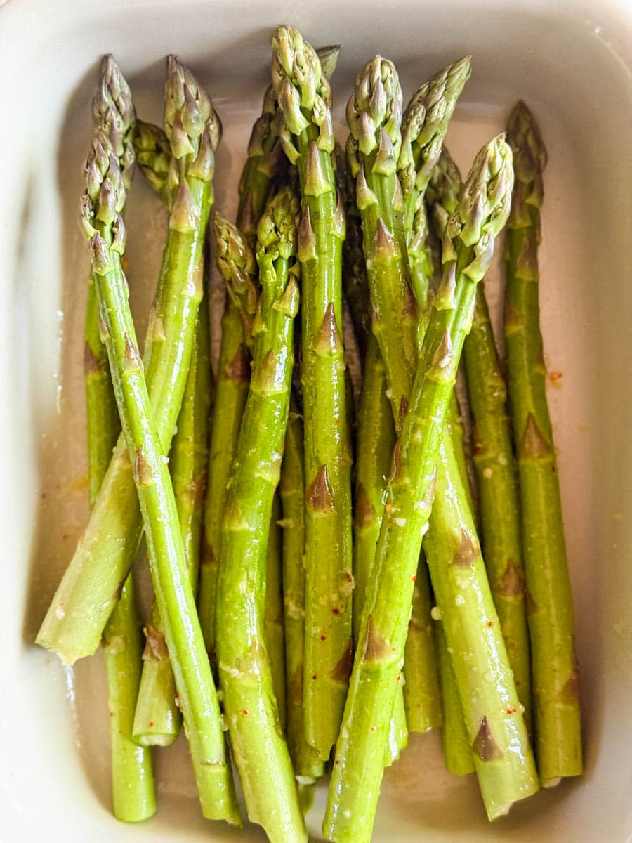 asperges enrobées d'huile, citron, piment et ail dans un plat