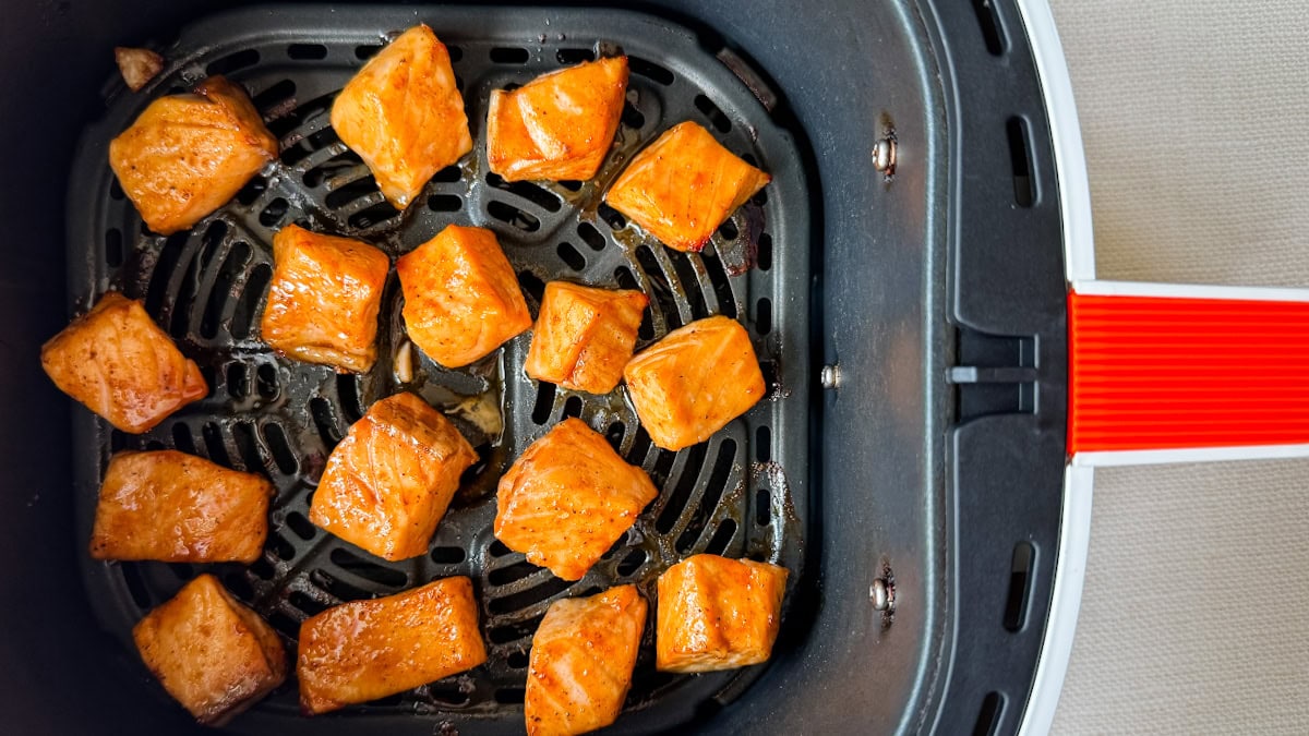 dés de saumon caramélisés sur la grille dans le panier d'un air fryer en gros plan