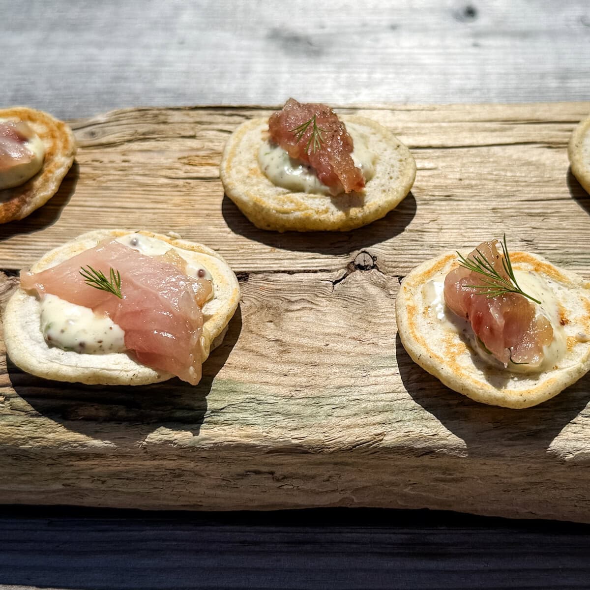 gravlax de maquereau sur petit blinis sur une planche de bois