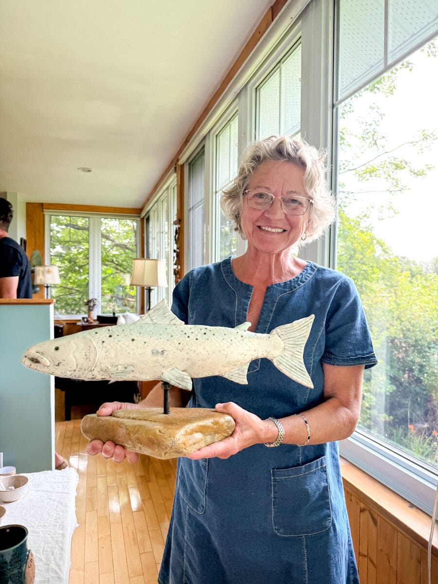 Monique artiste potière de barilocopots tenant son saumon en poterie