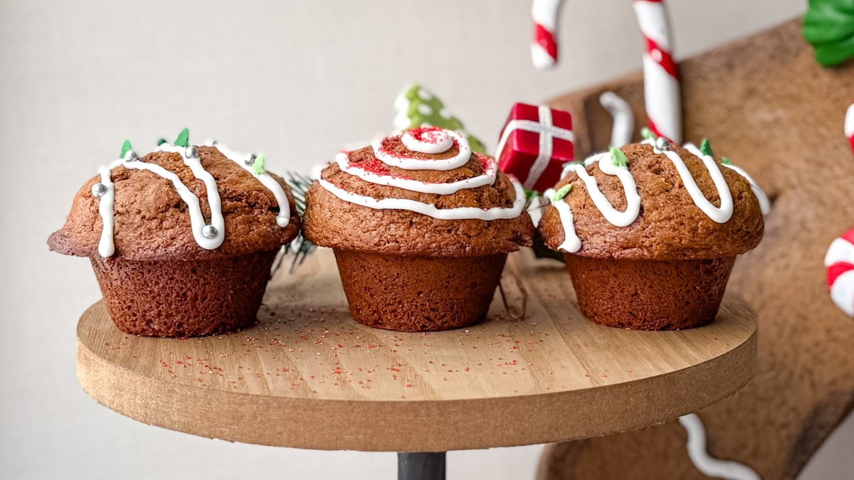 3 muffins pain d'épices sur planche de bois, décorés de glacage et sparkles de Noël