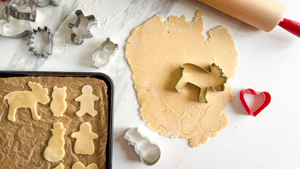 pâte, biscuits emporte-pièce, emportes-pièces et rouleau à pâtisserie sur comptoir blanc marbé