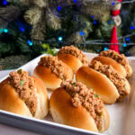 petits pains fourrés à la viande dans un plateau devant un arbre de Noël